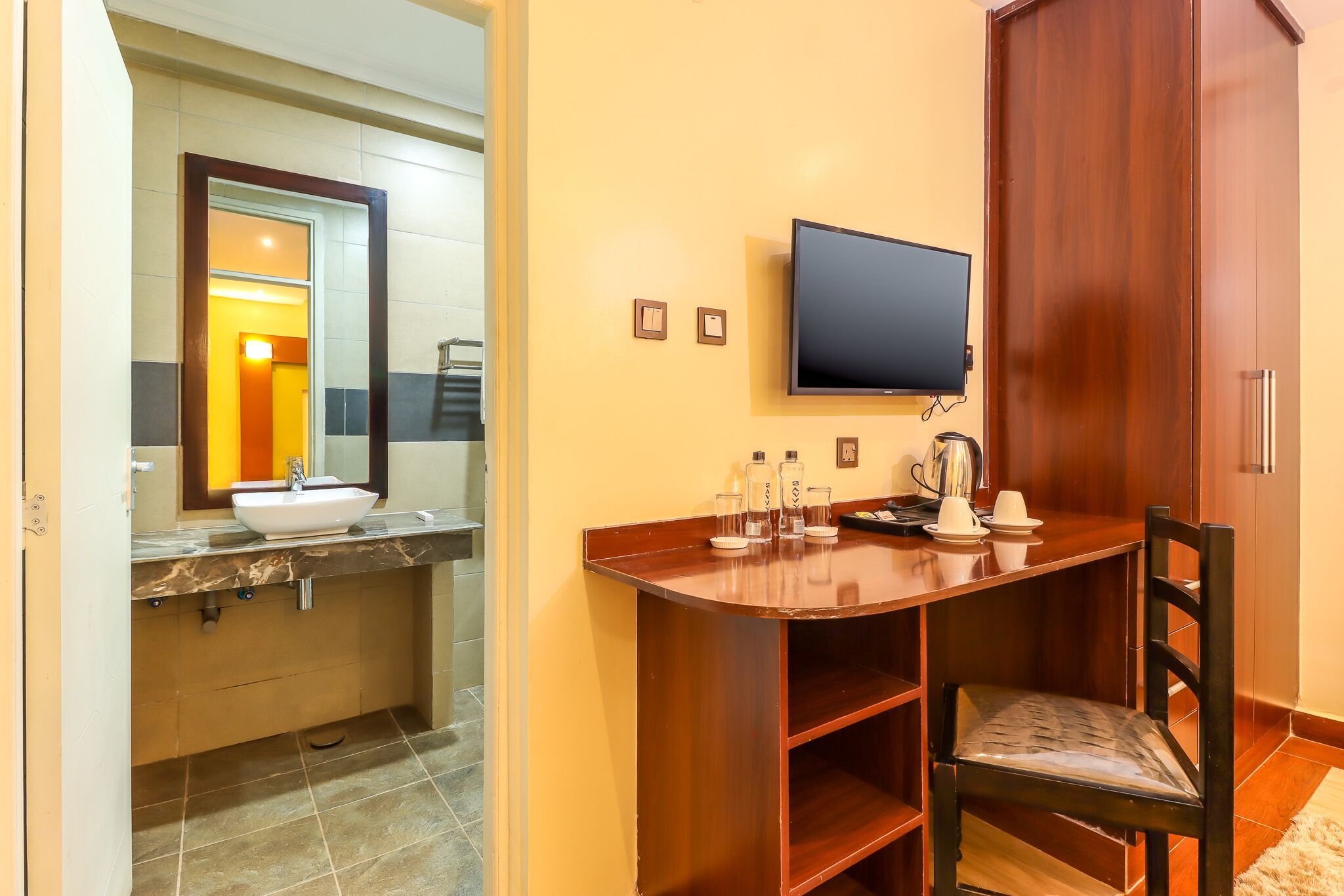 A bathroom with a sink, mirror, and television.