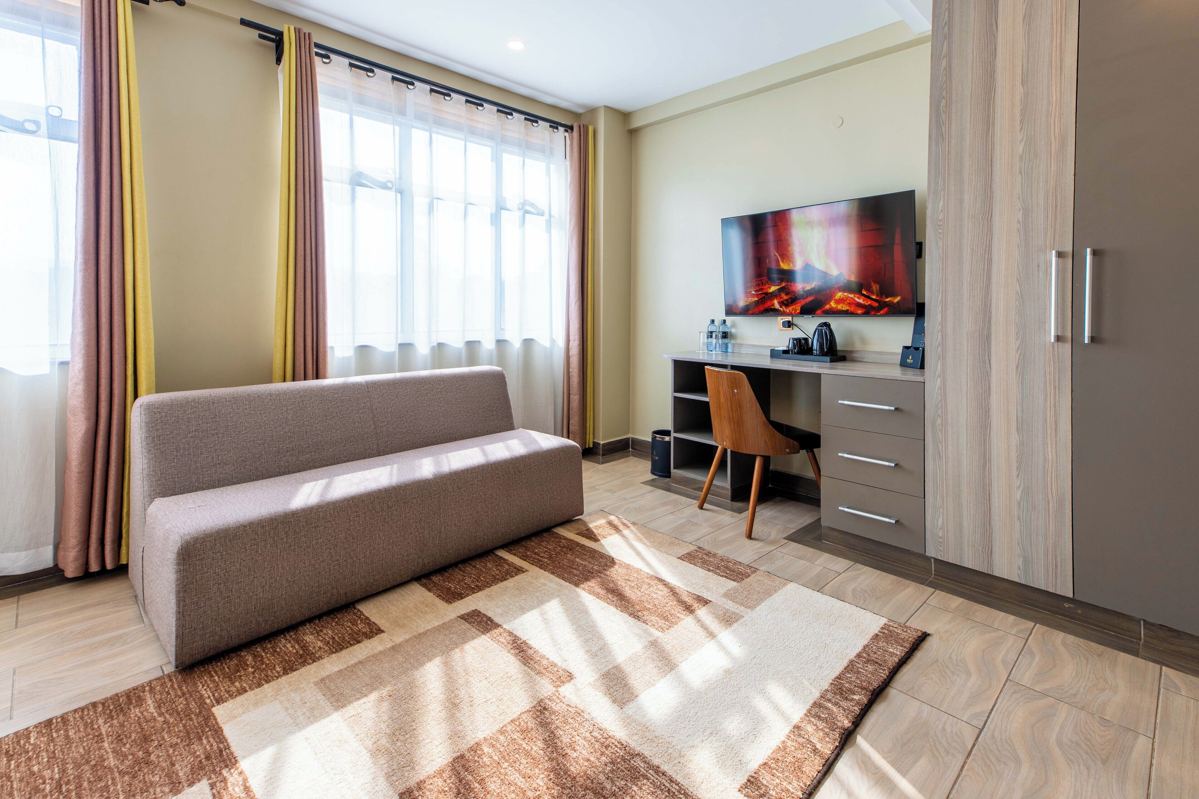 Ett modernt rum med en soffa, ett skrivbord med en stol, en tv och en garderob.