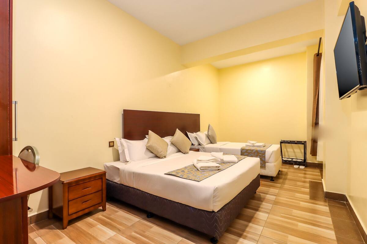A hotel room with a large bed, bedside tables, a TV, and a desk.