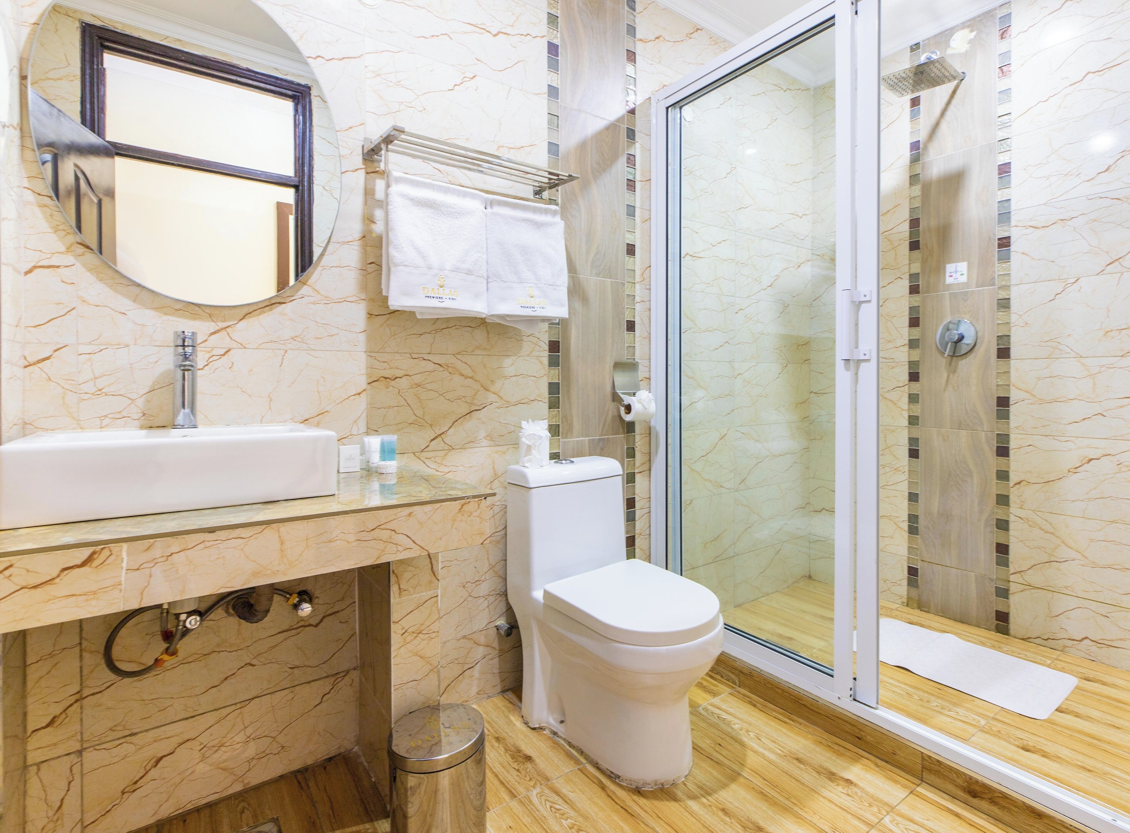 A bathroom with a marble sink, toilet, and glass shower enclosure.