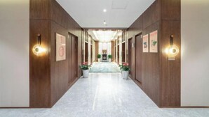 Un couloir d’hôtel avec des lambris en bois, un sol en marbre et des appliques murales.