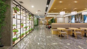 Un hall d’hôtel moderne avec un sol en marbre, des sièges en bois et un mur végétal.