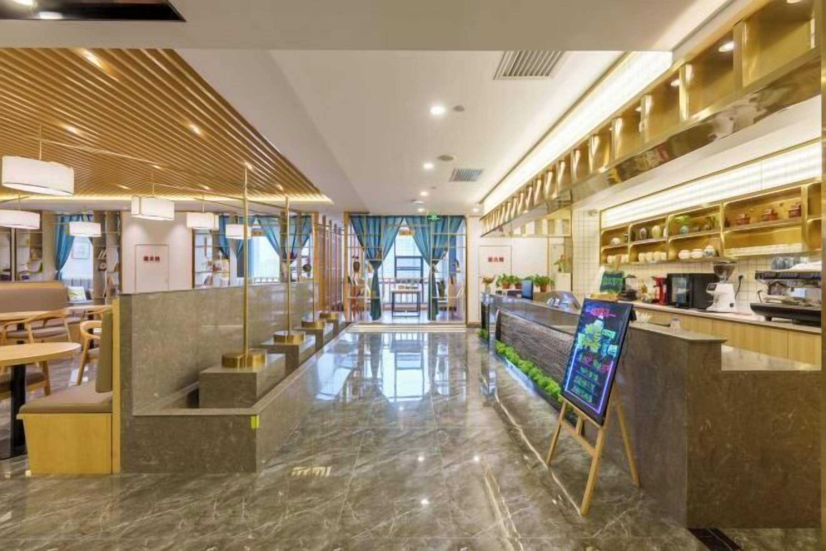 Un moderno vestíbulo de hotel con suelo de mármol, detalles de madera y un mostrador de recepción con una pantalla digital.