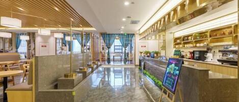 Un moderno vestíbulo de hotel con suelo de mármol, detalles de madera y un mostrador de recepción con una pantalla digital.