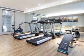 Un gimnasio con cintas de correr, bicicletas estáticas y una máquina de remo.