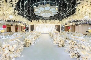 A banquet hall with a central aisle, tables on either side, and a ceiling with hanging lights. - Xijian Hotel (Baoji)