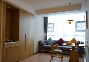 A modern living room with a sofa, a dining table, and a wooden cabinet. - Xijian Hotel (Baoji)
