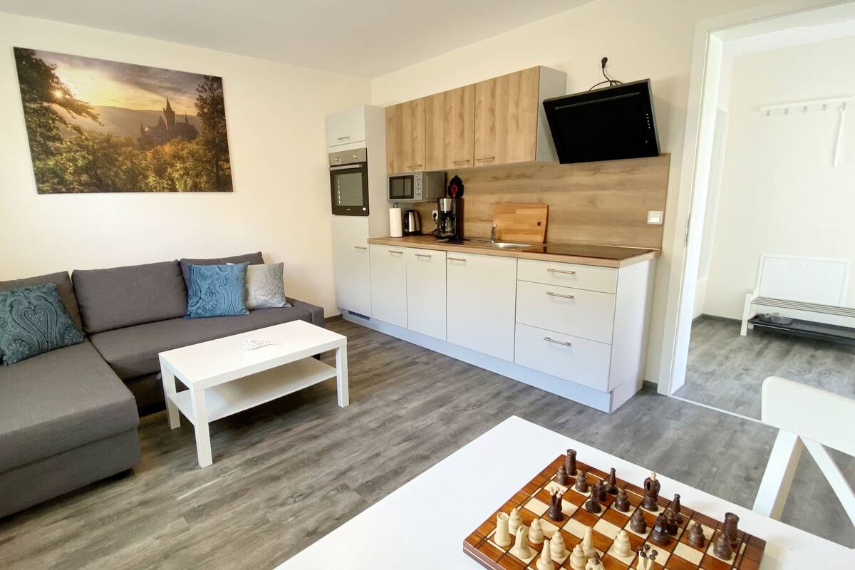 A modern living room with a grey sofa, a white coffee table, and a chessboard.