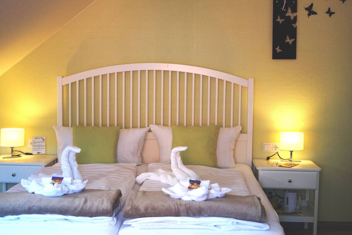 A hotel room with a bed, two nightstands, and a wall clock.