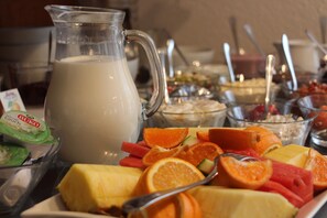 A breakfast buffet with a pitcher of milk, various fruits, and a bowl of yogurt. - Regiohotel Pfälzer Hof Wernigerode (Wernigerode)