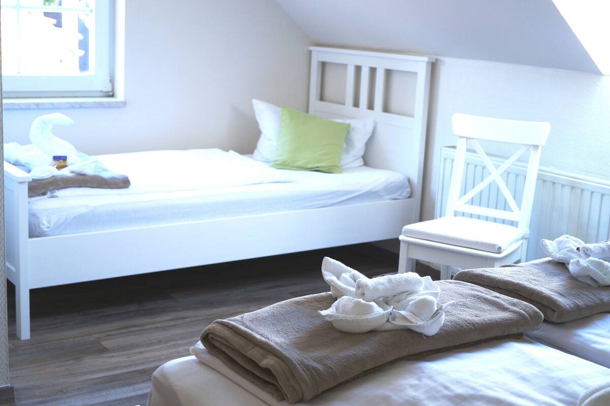 A neatly made bed with pillows and a folded towel on the floor.