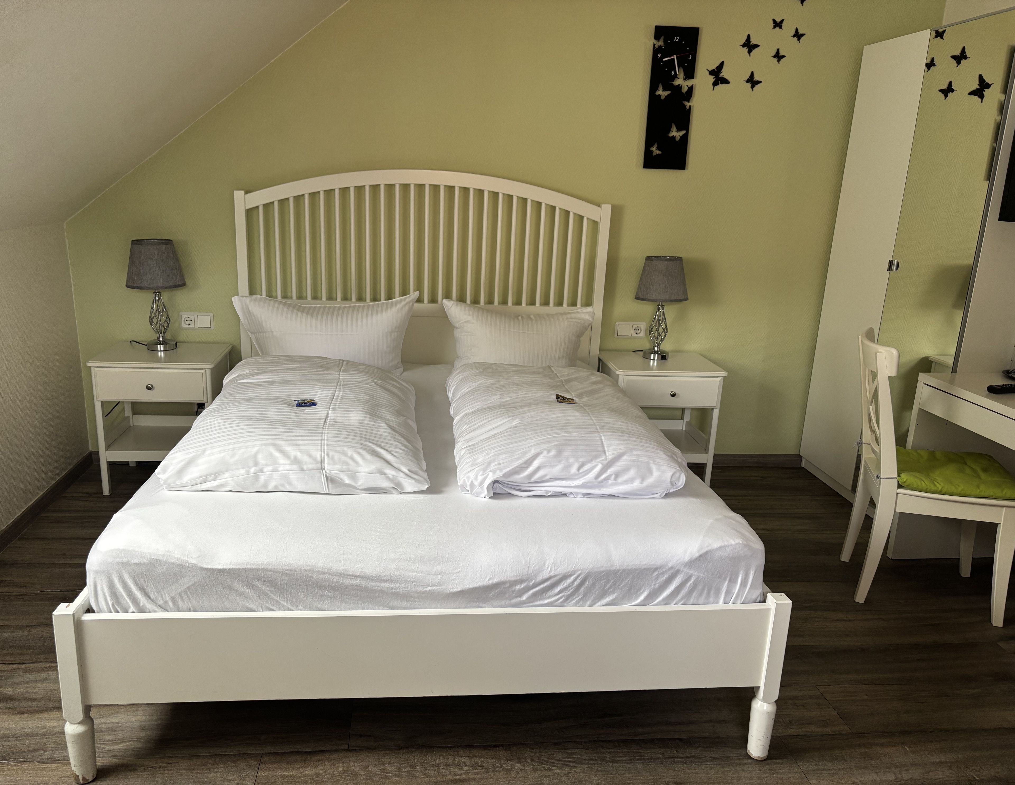 Una cama individual bien hecha con ropa blanca en una habitación con techo inclinado.