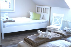 Una cama bien hecha con almohadas y una toalla doblada en el suelo.