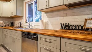 Une cuisine moderne avec des meubles de couleur gris clair, un plan de travail en bois et un lave-vaisselle.
