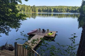 Une jetée en bois s’étendant sur un lac paisible, entouré d’une forêt dense.