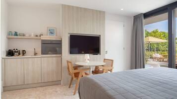 Una habitación de hotel moderna con una cama grande, una kitchenette, un comedor y un televisor.