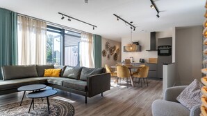 Ein modernes Wohnzimmer mit einer Eckcouch, einem kleinen Couchtisch und einem Essbereich mit Stühlen.