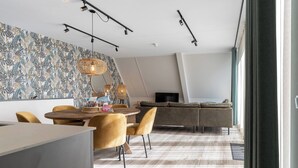 Ein modernes Wohnzimmer mit einer Couch, einem Fernseher und einem Essbereich mit Tisch und Stühlen.