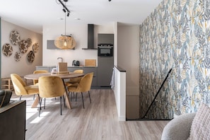 Une cuisine moderne dotée d’un four encastré et d’un coin repas avec une table ronde et des chaises jaunes.