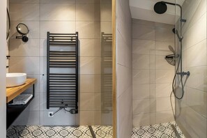 A bathroom with a towel rack, a sink, and a shower area. - Apartment with sauna near the beach | Duno Lodge 15-A (Oostkapelle)