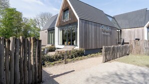 Ein modernes Gebäude mit Satteldach und einer hölzernen Umzäunung davor.