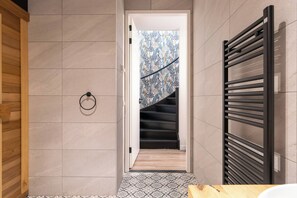 Une salle de bain moderne avec un plancher en bois, un porte-serviettes noir et un rideau de douche à motifs.