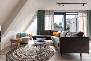A modern living room with a sectional sofa, a small round table, and a patterned rug.