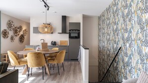 Eine moderne Küche mit Backofen und einem Essbereich mit rundem Tisch und gelben Stühlen.