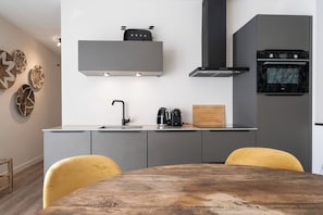 Une cuisine moderne avec des meubles de couleur grise, une table en bois et une chaise jaune.