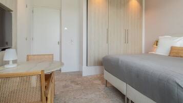 Un dormitorio con cama, mesita de noche con lámpara, armario y televisor.