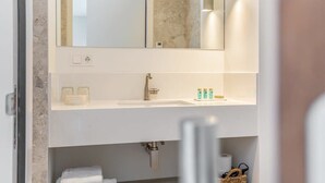 A bathroom with a large mirror, a sink, and a towel rack.