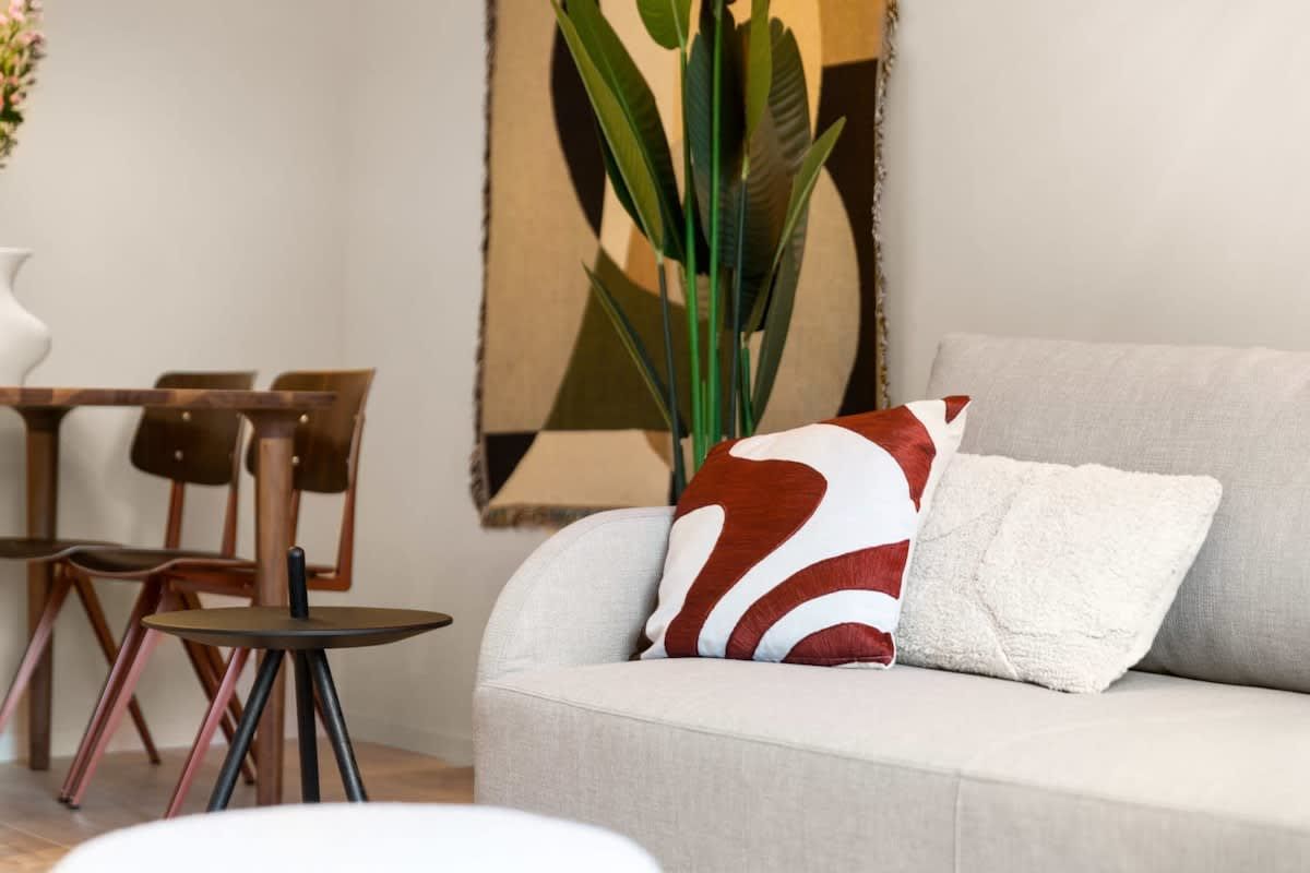 Una sala de estar con sofá, mesa, sillas y una planta grande.