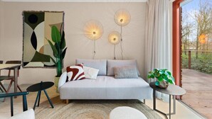 A modern living room with a sofa, a dining table, and a potted plant. - Apartment in the centre of Domburg | Duinenburg 10-3 (Domburg)