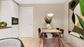 Un comedor con una mesa, sillas, un florero con flores e iluminación colgante.