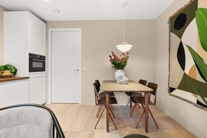 Un coin repas comprenant une table, des chaises, un vase avec des fleurs et un luminaire suspendu.