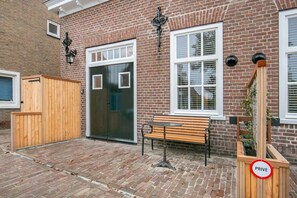 En byggnad av tegel med en träbänk, en stängd dörr och en skylt med texten ”PRIVAT”.