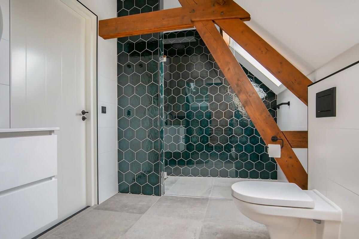 A modern bathroom with a glass shower enclosure, a wooden ceiling beam, and a white toilet.