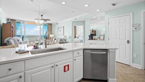 A modern kitchen with white cabinetry, a built-in dishwasher, and a ceiling fan. - Luxury Beachfront condo - 3 Bedroom, 3 full Bath, 2 master suites, sleeps 8. (Gulf Shores)