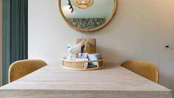 A dining table with a wicker basket containing a bottle, a bag, and some items.