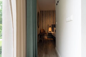 Ein Hotelzimmer mit Holzboden, einem Bett, einem Stuhl, einem kleinen Tisch und einer Wandleuchte.