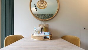 A dining table with a wicker basket containing a bottle, a tissue, and some food items. - Apartment near the beach in Oostkapelle | Duno Lodge 15-G (Oostkapelle)