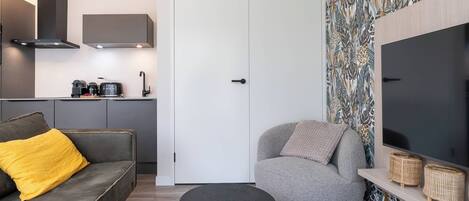 Una sala de estar moderna con un sofá gris, un sillón gris, un televisor de pantalla plana y una pared con diseño.