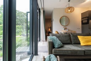 Ein modernes Wohnzimmer mit einem grauen Sofa, einem runden Spiegel und einem Essbereich mit Tisch und Stühlen.