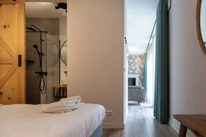 Une chambre avec un lit, une porte en bois, un espace douche et une vue sur un balcon.
