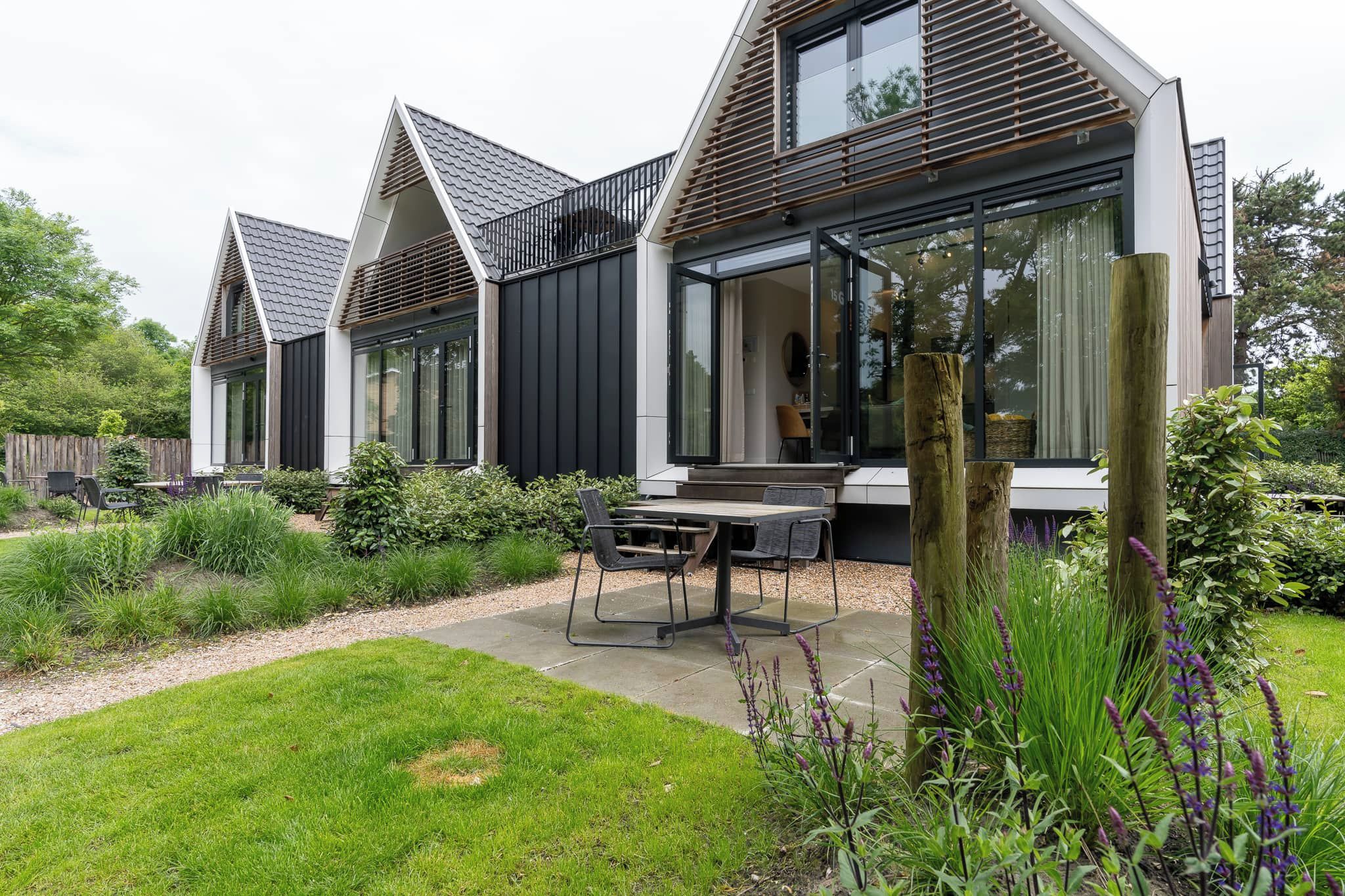 A modern house with a patio area featuring a table and chairs.