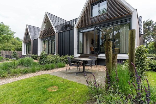 Ein modernes Haus mit einer Terrassenanlage, inklusive Tisch und Stühlen.