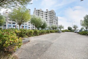 A multi-story residential building with balconies, a parking lot, and a row of parked cars. - Apartment with Sea Views in Breskens | Port Scaldis 19-031 (Breskens)