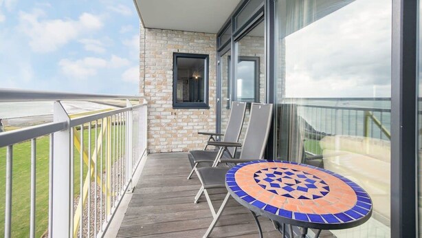 En balkon med udsigt til himlen, et flisegulv, et bord og to stole.