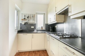 A compact kitchen with a gas stove, a coffee maker, and a window above the sink. - Apartment with Sea Views in Breskens | Port Scaldis 19-031 (Breskens)