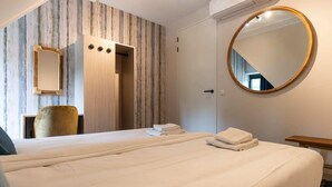 Una habitación de hotel con una cama grande, un espejo redondo, un armario y una silla.
